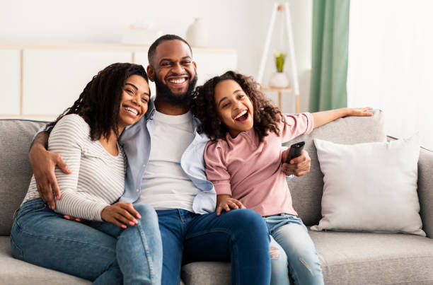 istock Happy young family watching television sitting on sofa 1307935765