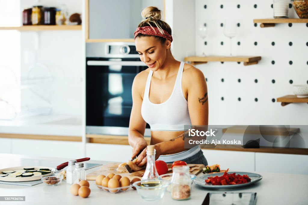 Nutrition is just as important as exercise. Young fit woman preparing meal in the kitchen. Healthy Eating Stock Photo