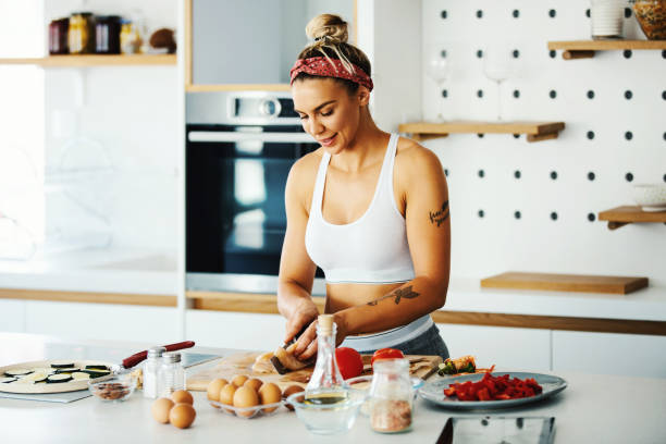 Nutrition is just as important as exercise. Young fit woman preparing meal in the kitchen. low carb diet photos stock pictures, royalty-free photos & images