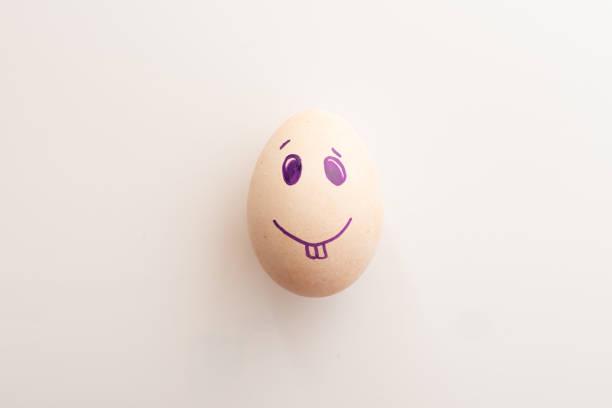 istock Easter egg on a white background. Egg with purple emoticon. face is painted on a white egg. preparing for Easter at home 1307936194