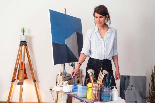 istock A young smiling painter in her studio smears paint with a paintbrush on a palette. 1307936926