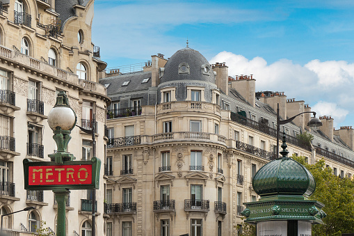 Typical Parisian (Hausmann) architecture, France. Metro sign and kiosk in the foreground