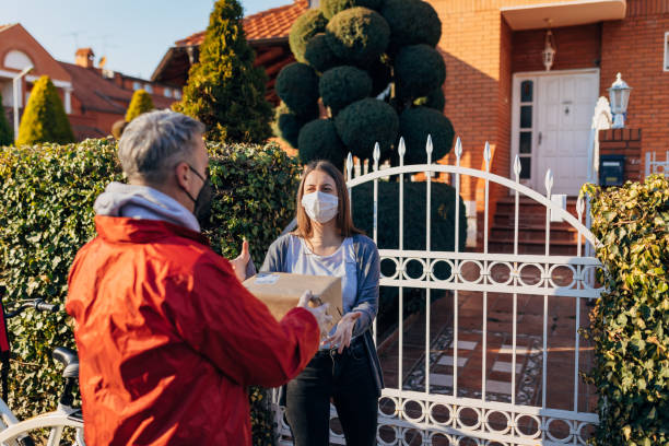 istock Responsible young woman ,receiving the delivery parcel, from a courier, while both wearing protective face mask as a new normal 1307938771