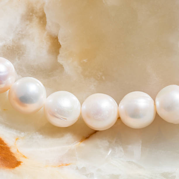 istock Nature white string of pearls on marble background in soft focus, with highlights 1307938978