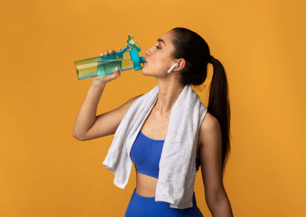 istock Sporty young woman drinking water from bottle at studio 1307939189