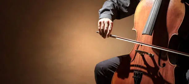 Cello player or cellist performing in an orchestra background isolated with copy space