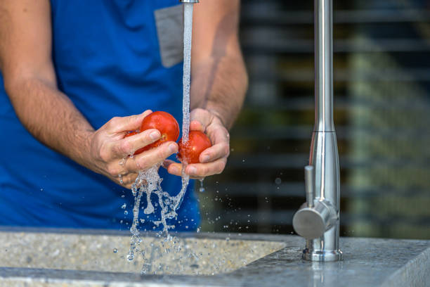 istock Man washing three tomatoes in running water 1307942789