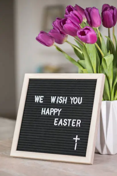 Spring concept. Bouquet of purple tulips flowers and letter board with the words We wish you  happy Easter. Happy Easter greeting card, gift, poster, web concept.