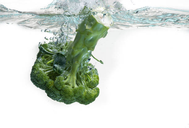 istock Close-up of broccoli splash into water isolated on white. 1307943173