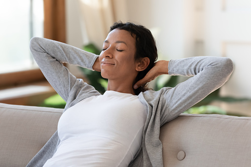 Close up of calm young African American woman relax sleep on sofa in living room with eyes closed. Relaxed biracial female rest on couch at home relieve negative emotions. Peace, stress free concept.