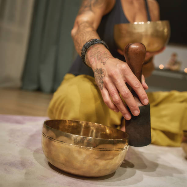 istock Young woman playing singing bowl while sitting on floor 1307944314