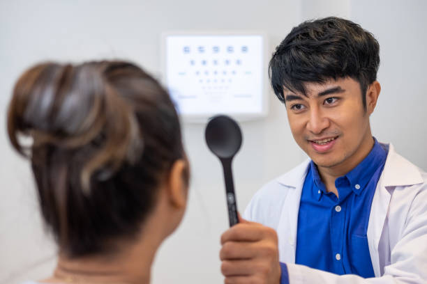 selective focus at optometrist face. while doctor using penlight and subjective refraction to  examine eye visual system of elder patient women with professional machine before made glasses. - penlight imagens e fotografias de stock