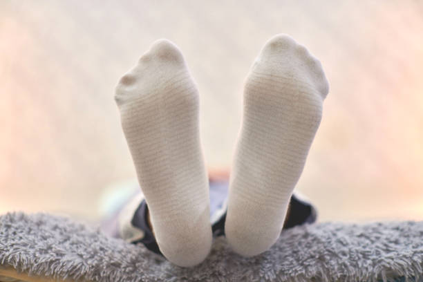 istock Woman resting on sofa in white striped socks, close up. 1307947892