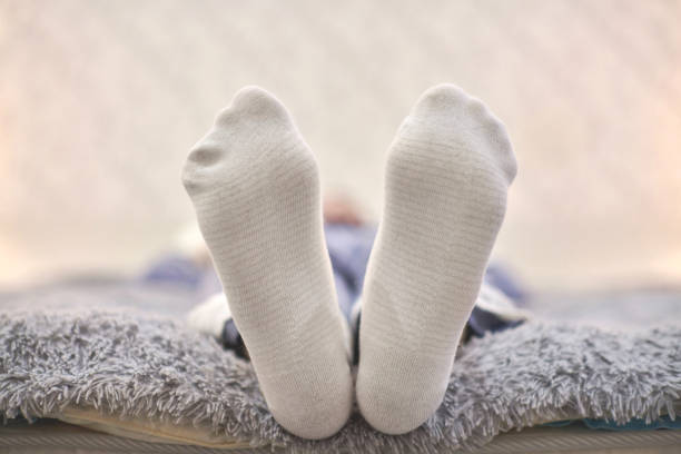 istock Woman resting on sofa in white striped socks, close up. 1307947904