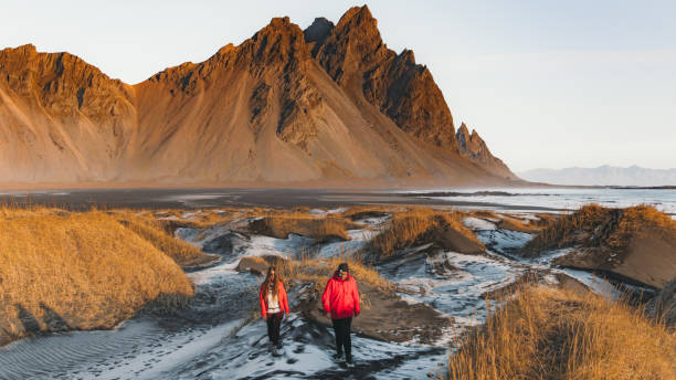młoda para turystów odkrywających malowniczy krajobraz dzikiej przyrody na islandii podczas jasnego wschodu słońca na świeżym powietrzu - sunrise beach couple hiking zdjęcia i obrazy z banku zdjęć
