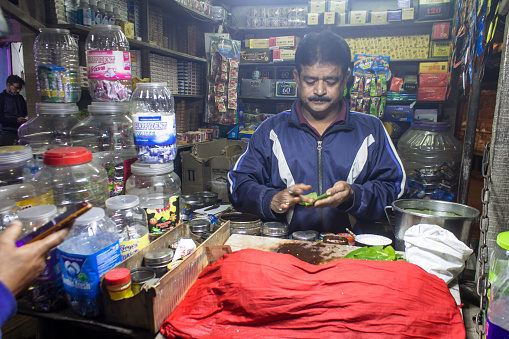 Kolkata, India - February 7, 2021: Pan or betel leaf seller making a pan for his customer in Kolkata.