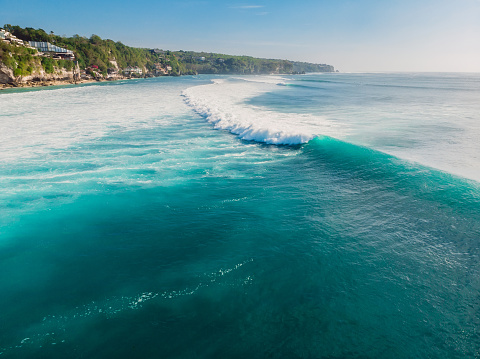 Blue wave in tropical ocean at Padang Padang, drone shot. Aerial view of barrel waves