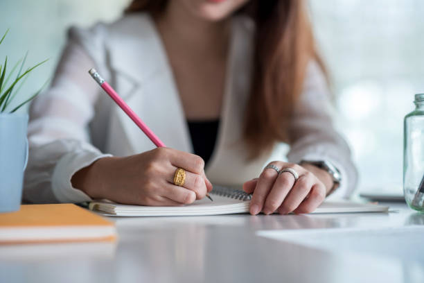 istock Close up. Businesswoman writing on a blank notebook on the table at office. 1307949652