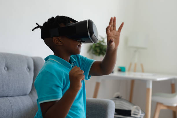 istock African american boy wearing vr headset sitting on couch and raising his hand 1307949721
