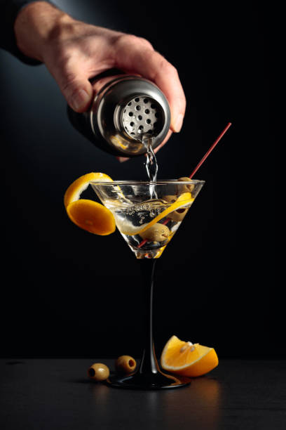 istock Dry martini with lemon peel and green olives on a black background. 1307950937