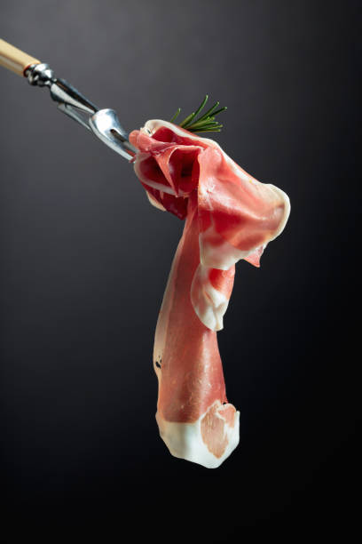 istock Sliced prosciutto with rosemary on a fork. 1307952519