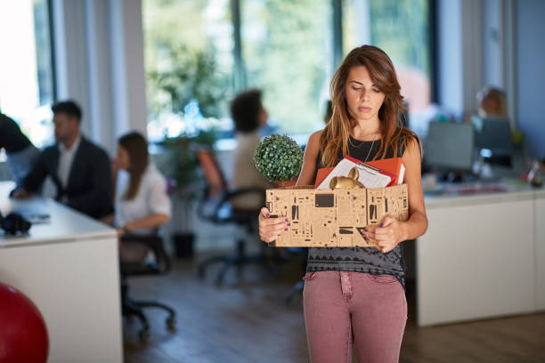 young female got fired and moving out of the office. end, new beginning young female got fired and moving out of the office, carrying her stuff in the box. end, new beginning being fired photos stock pictures, royalty-free photos & images