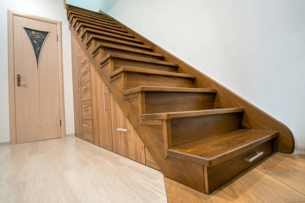 istock Modern architecture interior with luxury hallway with glossy wooden stairs in multi-storey house. Custom built pullout cabinets on glides in slots under stairs. Use of space for storage. 1307957722