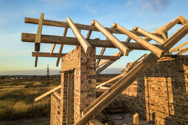 istock Private residential house with wooden roof frame structure under construction. Unfinished brick building under development. 1307957741