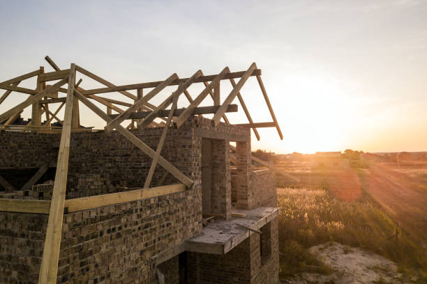 istock Private residential house with wooden roof frame structure under construction. Unfinished brick building under development. 1307957742