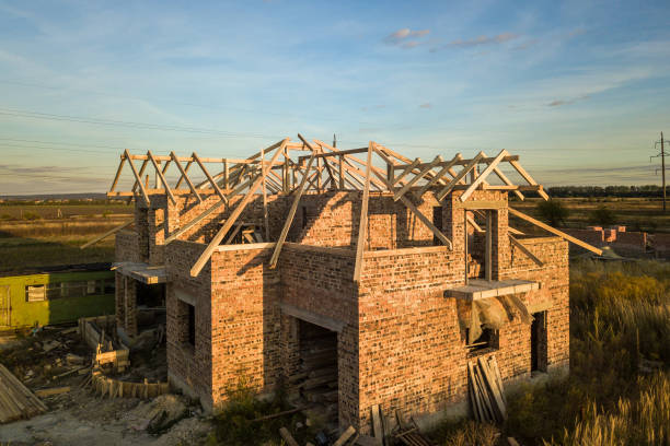 istock Private residential house with wooden roof frame structure under construction. Unfinished brick building under development. 1307957746