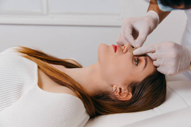 Doctor examining patient nose after rhinoplasty surgery, medical operation stock photo