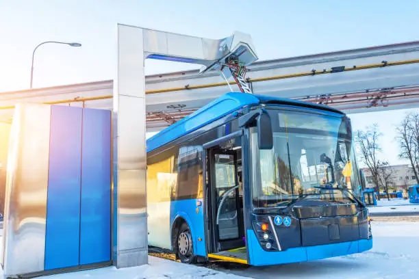 High-voltage electric charging station for charging electric buses at the final stop of the city route. Bus at the final stop with an open door