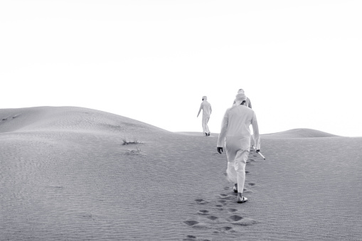 Black and White image of Arabs climbing the dunes of Arabia