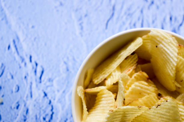 istock Potato chips in a bowl on a blue background 1307961704