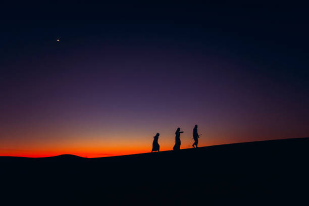 Arabs climbing the sand dunes Arabs walking over Sand dune during dusk arabian desert stock pictures, royalty-free photos & images