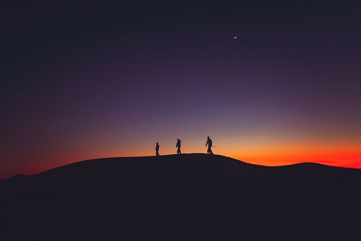 Arabs walking over Sand dune during dusk