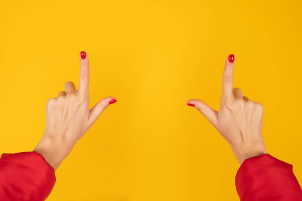 istock Female hands pointing up on yellow background. Red fingernails, hand sign. 1307963757