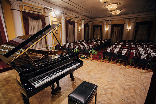 Grand Piano on stage in empty concert hall, no people.