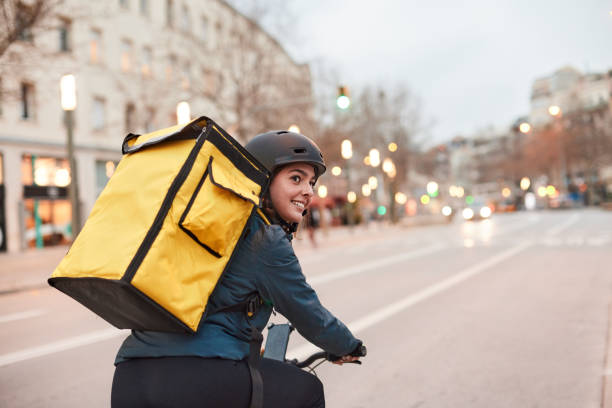 un motociclista di delivery che si guarda alle spalle. - corriere foto e immagini stock