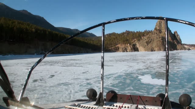 Airboat air glider moves to mountain coast on ice of Lake Baikal.