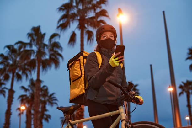 밤에는 코디 보호 마스크를 가진 배달 자전거 타는 사람과 함께 제공됩니다. - bicycle messenger 뉴스 사진 이미지
