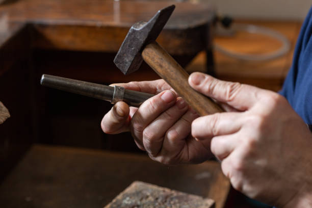 istock foreground, hammer hammering a silver ring to shape it in a jewelry workshop. 1307967558