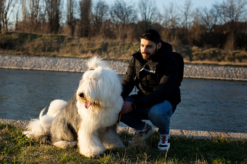 Handsome young man posing with his dog near river