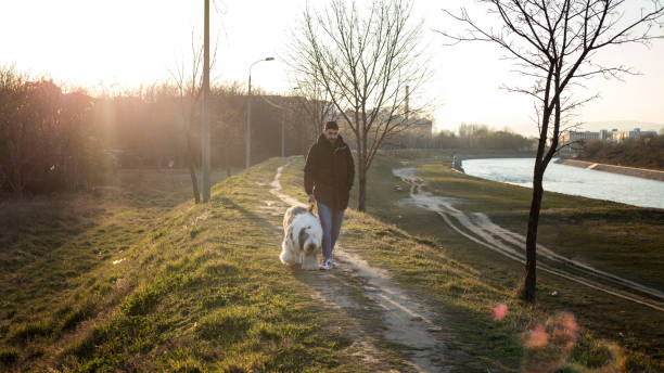 istock Handsome young man posing with his dog near river 1307971398