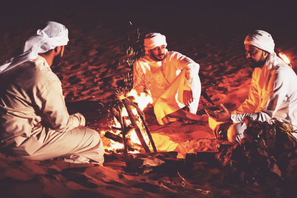 amici arabi seduti intorno al falò in un campo nel deserto - friendship camping night campfire foto e immagini stock