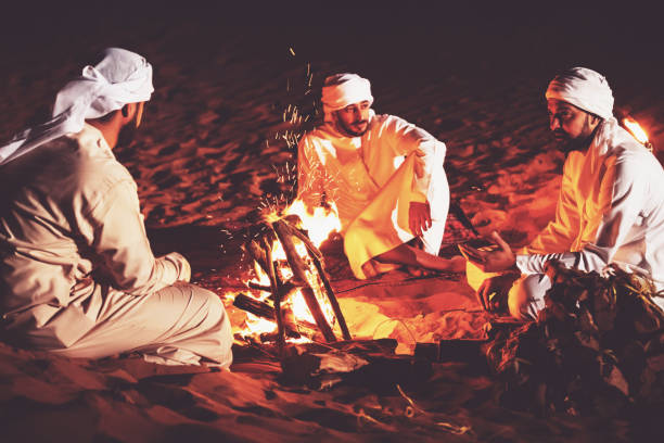 istock Arab friends seated around campfire at a desert camp 1307975067