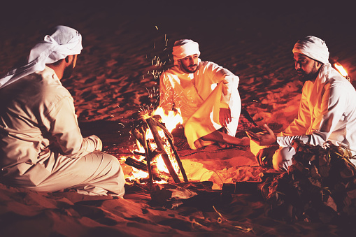 Arabs seated around campfire and enjoying casual conversation