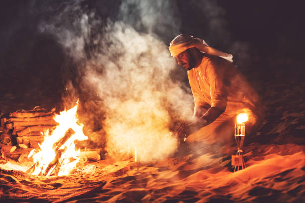 istock Arab man starting a kebab grill at a desert camp 1307975265
