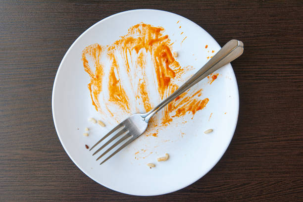 istock Dirty dish with food remnants with red sauce. White plate and fork, on a table. 1307975687