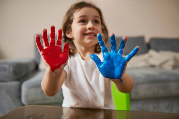 concéntrate en las manos pintadas en pinturas azules y rojas de una linda niña - oil painting painted image art studio fun fotografías e imágenes de stock